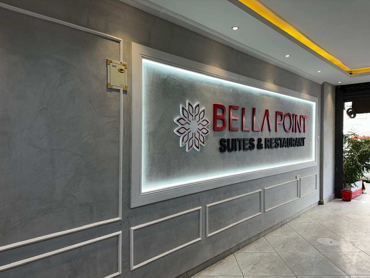 The Bellapoint Suites lobby, its red and black lettered sign set in a white-framed, backlit panel on a grey wall.